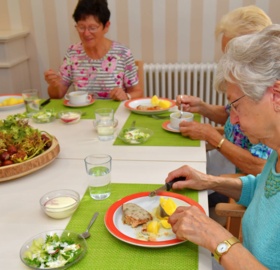 Gemeinsames Essen im St. Bonifacius Wohn- und Pflegeheim Unna an einem grün eingedeckten Tisch