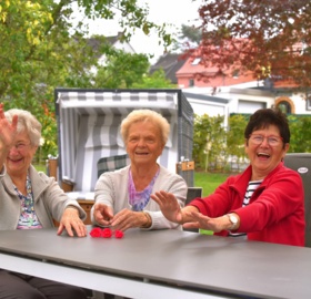 Drei lächelnde Bewohnerinnen des St. Bonifacius Wohn- und Pflegeheim Unna die gemeinsam an einem Tisch sitzen